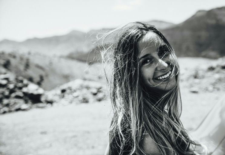 Femme appliquant un soin capillaire naturel sur ses cheveux devant un miroir