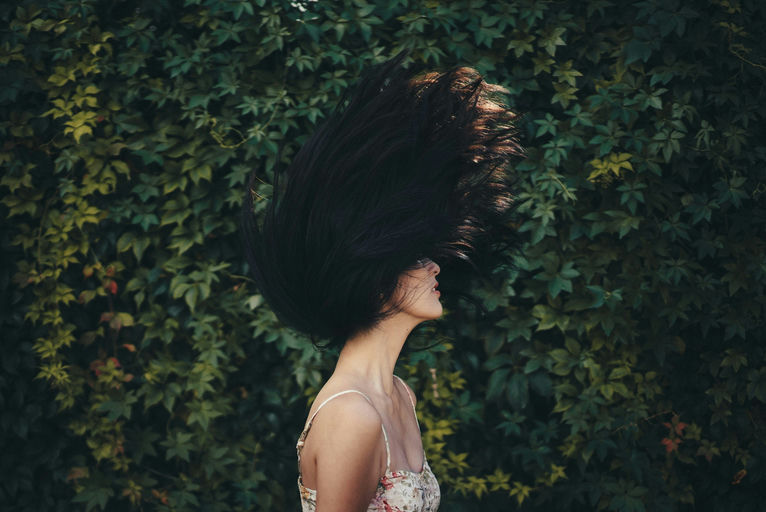 Image montrant une femme avec des cheveux brillants et sains, entourée de produits capillaires naturels, représentant un mode de vie équilibré et des soins capillaires naturels.