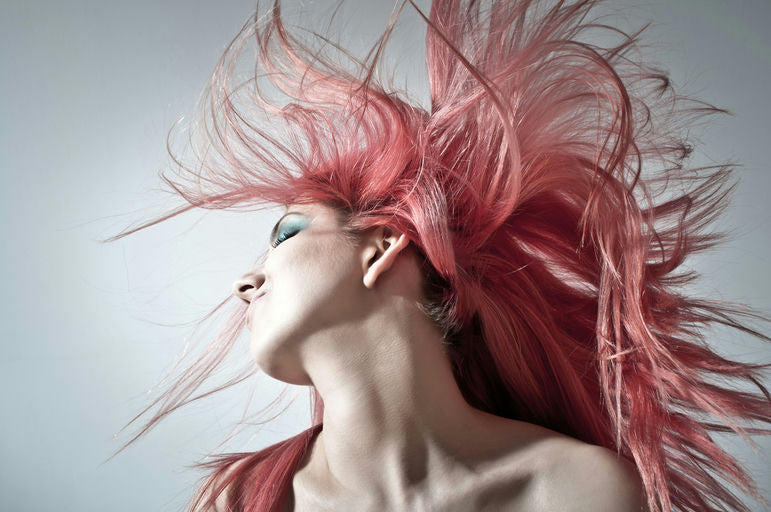 Femme appliquant de l'huile capillaire naturelle sur ses cheveux pour des soins revitalisants et hydratants.